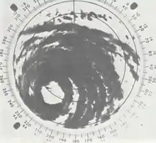 Black and white radar image of a tropical cyclone; gray areas denote areas where rainfall is occurring. Although only a portion of the tropical cyclone is visible, rainbands and a central eye feature can be clearly made out.