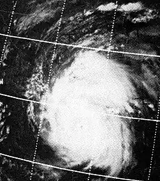 A satellite image of a hurricane. A small eye is visible. An overlay of the coordinate grid is also visible.