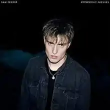 A Caucasian man in a black shirt and a denim jacket is shown, amidst a black background. "Sam Fender" and "Hypersonic Missiles" are displayed in white text in the top left and top right corners, respectively.