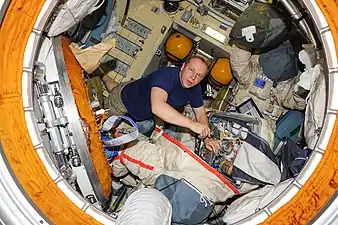 Cosmonaut Oleg Kotov works with a Russian Orlan spacesuit in the Pirs Docking Compartment.