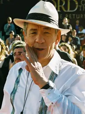 A photograph of Ian McKellen, a man wearing a white collared shirt and hat