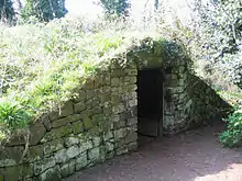 A stone structure with an archway, covered in turf