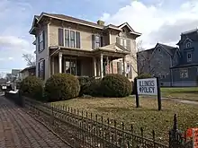 Large brown two story wooden houwe with sign in yard reading "Illinois Policy"