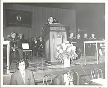 William Birenbaum at his inauguration as President of Staten Island Community College. September 30, 1969. He is wearing graduation regalia and speaking at a podium.