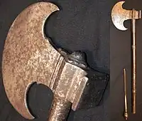 Sindhi tabar battle axe, late 18th century or earlier, crescent shape 12 cm (5 in) long head with a square hammer opposite of the blade, 55 cm (22 in) long steel haft, the end of the haft unscrews to reveal a 12 cm (5 in) slim blade. Heavily patinated head and handle with traces of engraving.