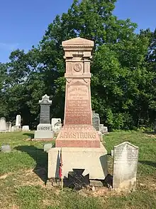 A tall brown polished obelisk-shaped stone monument