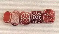 Indian carnelian beads with white design, etched in white with an alkali through a heat process, imported to Susa in 2600-1700 BCE. Found in the tell of the Susa acropolis. Louvre Museum, reference Sb 17751. These beads are identical with beads found in the Indus Civilization site of Dholavira.