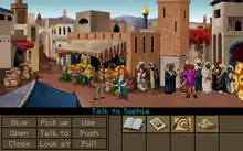 A video game screenshot showing the two protagonists in the middle of a crowded marketplace. The lower part of the image shows a variety of objects on the right side and a number of verbs such as "Pick up", "Use" and "Talk to" on the left side. The mouse cursor is pointing at Sophia, making the current command "Talk to Sophia".