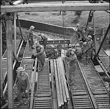 A photograph showing a number of Royal Engineers sappers constructing an Inglis Bridge across a river