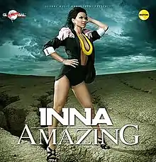 Inna wearing a black coat and leotard with high heels and a yellow necklace.