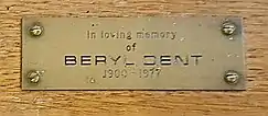 A brass plaque on the bishop's chair, situated close to the altar in the Church of St Mary the Blessed Virgin, Sompting, bearing a memorial to Dent with the following inscription: "In loving memory of BERYL DENT 1900 – 1977".