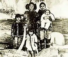 Two women and three children, wearing Inuit clothing, smiling and grouped for a photograph
