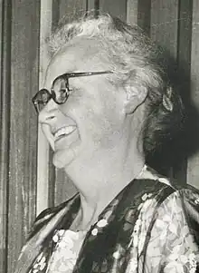 Monochrome portrait of Hardwich. She is shown in profile and looking to the left. She is wearing glasses and a blouse decorated with flowers.