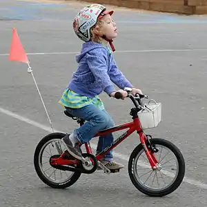 Four year old on Cnoc 14, US coaster brake version, with third party basket and flag