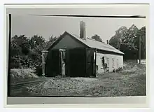 A single story building with two large doors. Train tracks lead into both doors.