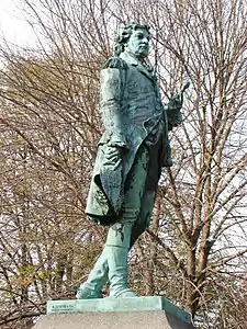 A color photograph of a bronze statue of a man