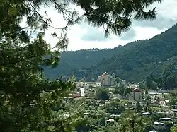 Distant view of the town, with a tree-covered mountain behind.