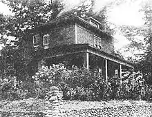 Black and white photo of two story house with a large patio on the first floor.