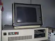 A 1980s white box IBM PC compatible with one full-height 5.25-inch drive bay containing a half-height 5.25-inch floppy drive