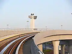 JFK Airport's control tower in the background and an AirTrain guideway in the foreground