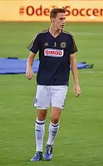 Soccer player Jack Elliott, wearing a dark blue Philadelphia Union jersey with white shorts and socks, on a soccer field during training.