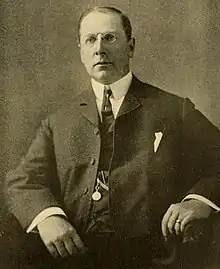 Black and white photo of James Hilton Manning in 1906, seated and wearing three piece suit
