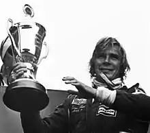 James Hunt celebrating a victory with a trophy in his right hand