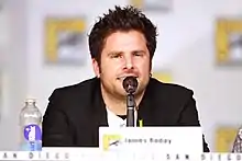 A man in a black jacket talking into a microphone