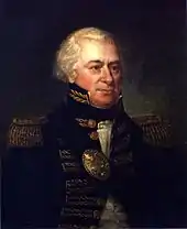 A man with white, receding hair in a high collared military coat with gold accents over a white shirt