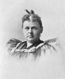 A white woman wearing a ruffled dress, hair in an updo