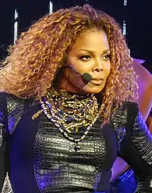 Janet Jackson performing in a black dress.