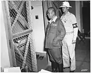 A military police officer, wearing a fiber helmet, escorting Imperial Japanese Army General Tomoyuki Yamashita during his war crimes trial in 1945