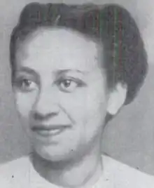 A smiling young Black woman, hair parted center and braided back, wearing a white top with a crew-style neckline