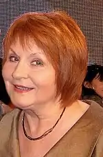 Close-up of Jędryka with red hair, smiling at the camera.