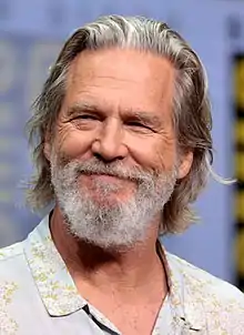 Aging Caucasian male with gray-white hair and a full gray beard.  His eyes are squinting from smiling, and he is wearing a light-colored collared shirt.