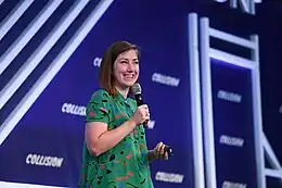 Jessica Hische speaking on stage at a conference in a green patterned dress