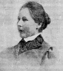 3/4 view of head and shoulders of middle-aged white woman with dark hair in bun