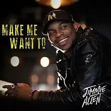 An image of a smiling man wearing a black baseball cap and leather jacket. The artist's name appears on the bottom-right corner in white and the song title is set beside the artist in yellow.