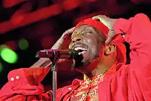 A man in red clothing singing into a microphone.