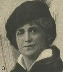 Photograph of a woman wearing a beret and a dark coat with a turned back white collar.