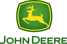 A green, rounded square with a yellow jagged outlines on the four sides of the square near the outside of its green border can be seen. In the middle of the yellow outline, a biological entity drawn outlined in yellow can be seen in a leaping position. This animal is commonly referred to as a deer. Underneath the deer and the green box, the words in caps lock, 'JOHN DEERE' can be read.