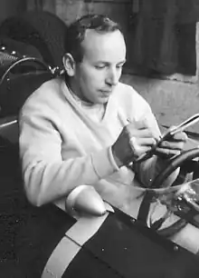 John Surtees signing an autograph in a racing car
