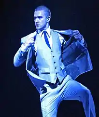 Justin Timberlake performing onstage, about to taking off his coat