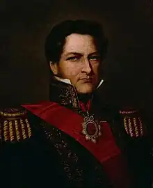 Half-length painted portrait of a man with curly hair, long sideburns and blue eyes who wears a heavily embroidered military tunic with high collar, gold braid epaulettes and a red sash of office