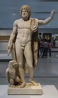Marble statue of a bearded man, standing, with his right arm raised above his head.