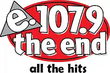 A red oval with a loose black outline. Atop it in the upper left is a gray triangle with a black outline and white lowercase letters "e." trimmed in black. On the rest of the oval, in white lowercase letters trimmed in black, is "107.9 the end" on two separate lines. Beneath is the slogan "all the hits" in black.