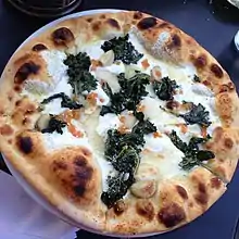 A pizza topped with kale and cheese