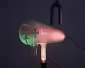 When the magnet is reversed, it bends the rays down, so the shadow is lower. The pink glow is caused by cathode rays striking residual gas atoms in the tube.
