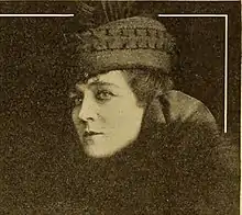 A woman with fair skin, wearing a hat