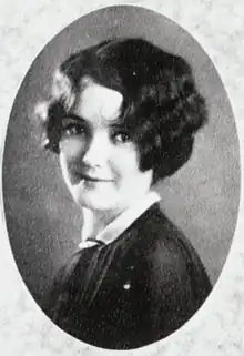 A young white woman with short wavy dark hair, in an oval frame